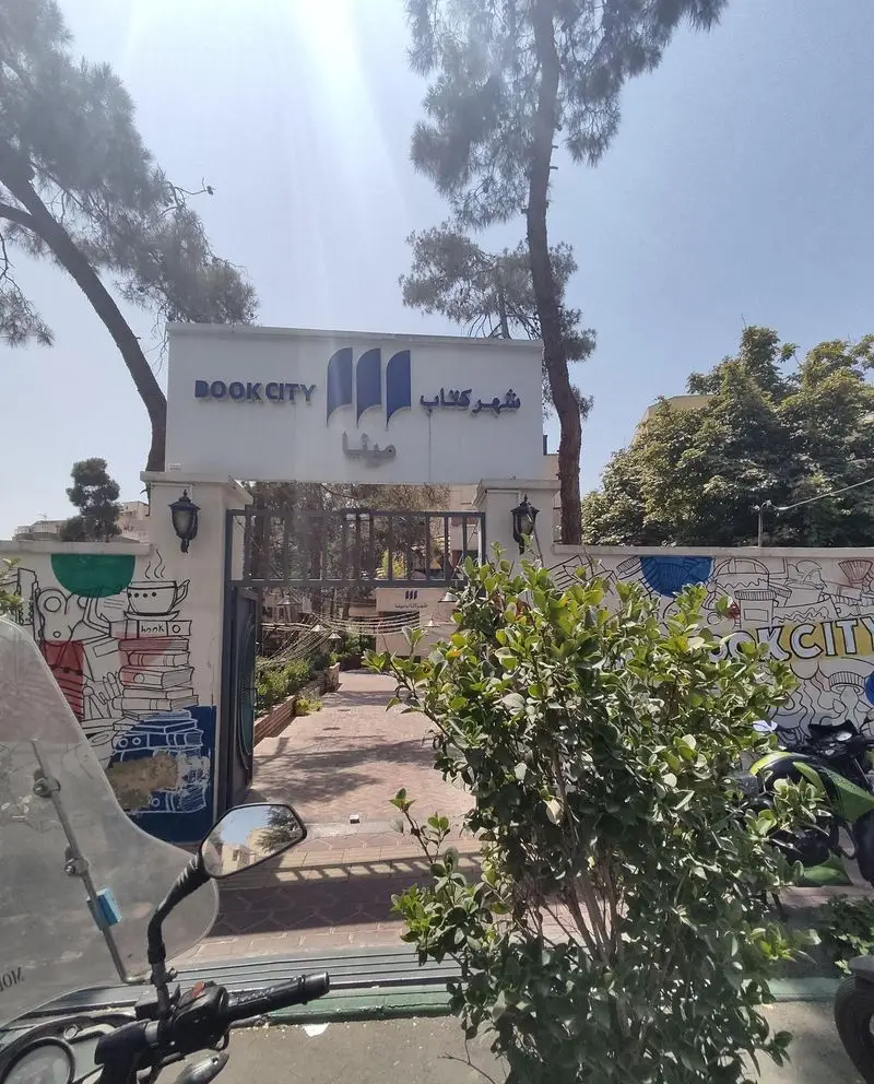 ورودی کافه هومان واقع در شهر کتاب، با تابلو "BOOK CITY" به دو زبان، دروازه آهنی و محوطه بیرونی دنج و باصفا.