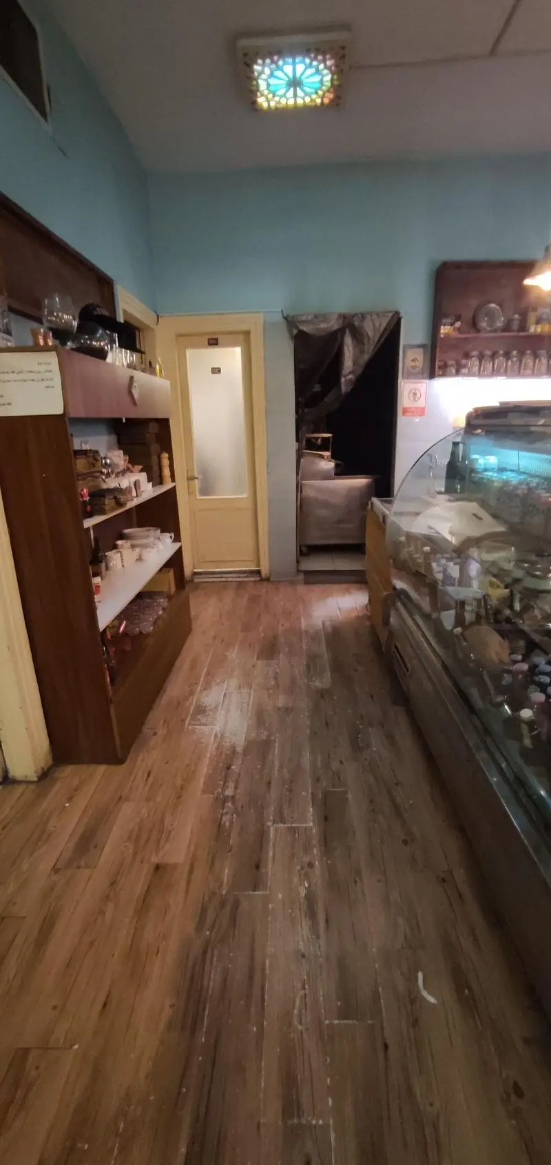 کافه حوض کاشی: نمای داخلی با سقف کاشی‌کاری جذاب، کفپوش چوبی و ویترین محصولات تازه. محیطی آرامش‌بخش برای لذت بردن از قهوه.