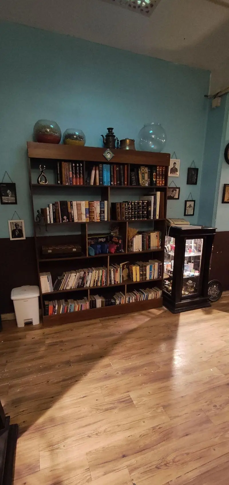 تصویری از قفسه کتاب چوبی و دکوراسیون منحصربه‌فرد کافه حوض کاشی، فضایی دنج و دلنشین برای مطالعه و ملاقات دوستان.