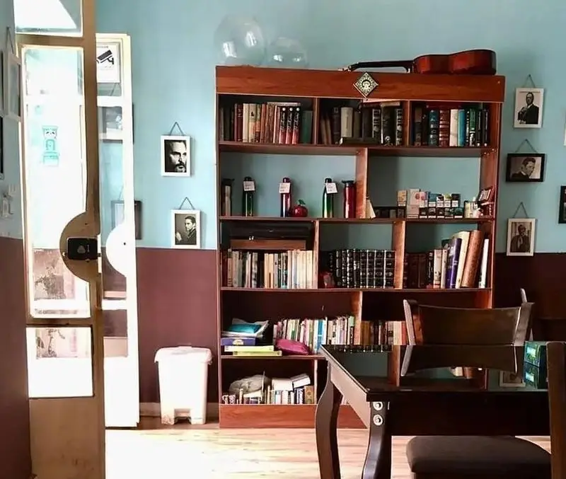 محیط دنج و فرهنگی کافه حوض کاشی، با قفسه‌های چوبی مملو از کتاب، گیتار، قاب عکس‌های کلاسیک و فضایی دلنشین برای مشتریان.