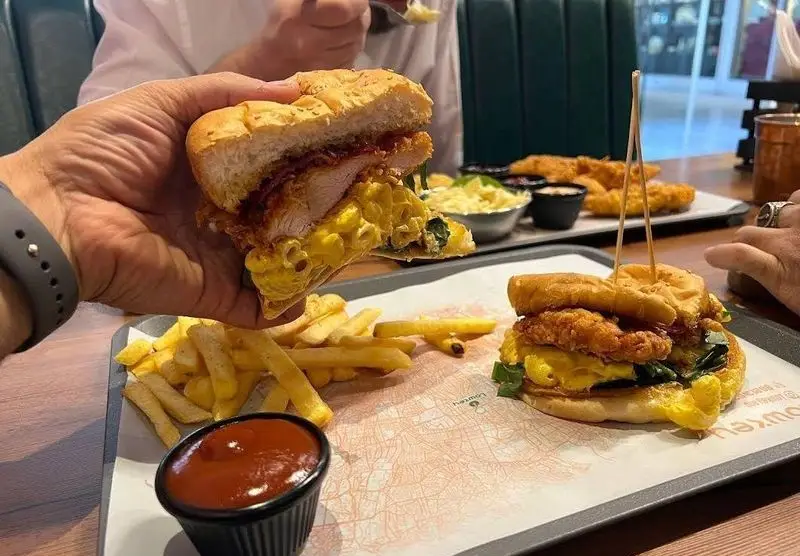 تصویری از ساندویچ‌های پرملات مرغ سوخاری و مک اند چیز در کافه رستوران لوکی، همراه با سیب زمینی سرخ کرده و سس کچاپ، مناسب برای یک وعده غذایی دلپذیر.