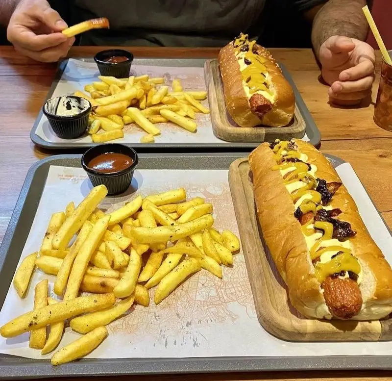 هات داگ‌های خوشمزه و سیب‌زمینی سرخ‌کرده ترد با سس خردل و کچاپ در کافه رستوران لوکی، ایده‌آل برای یک وعده فست فود کامل.