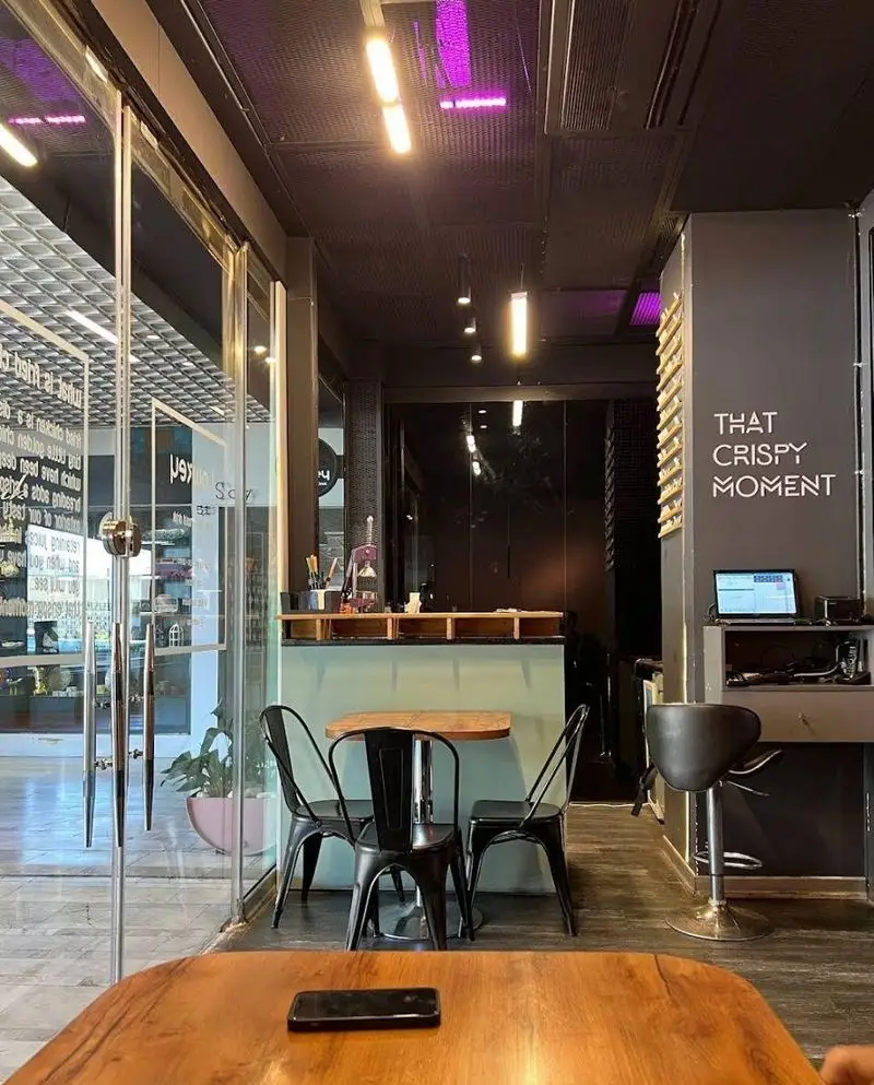 نمای داخلی کافه رستوران لوکی، با طراحی مدرن و نورپردازی جذاب، میزهای چوبی و صندلی‌های مشکی، آماده پذیرایی از مشتریان.