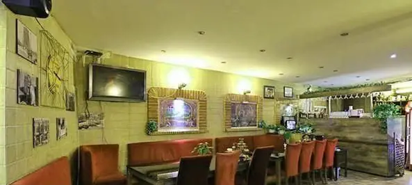 تصویری از فضای داخلی دنج کافی شاپ دلنوازان با دکوراسیون گرم، مبلمان راحت، نورپردازی ملایم و تابلوهای هنری، مکانی ایده آل برای استراحت.