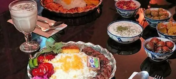 سفره‌ای پر از غذاهای لذیذ ایرانی شامل کباب، برنج و انواع دورچین در کافی شاپ دلنوازان. تجربه‌ای به یادماندنی از طعم اصیل.