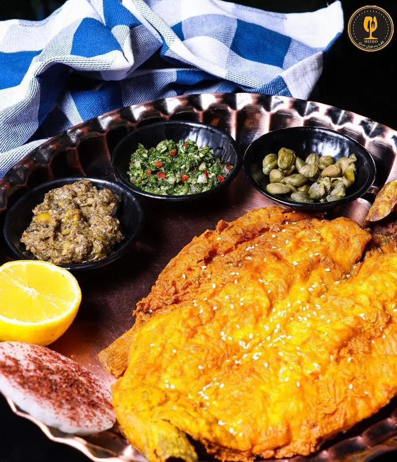 ماهی سرخ شده ترد و طلایی با کنجد، لیمو تازه و چاشنی‌های خاص در کافه رستوران میژو. تجربه‌ای دلپذیر از غذای دریایی.