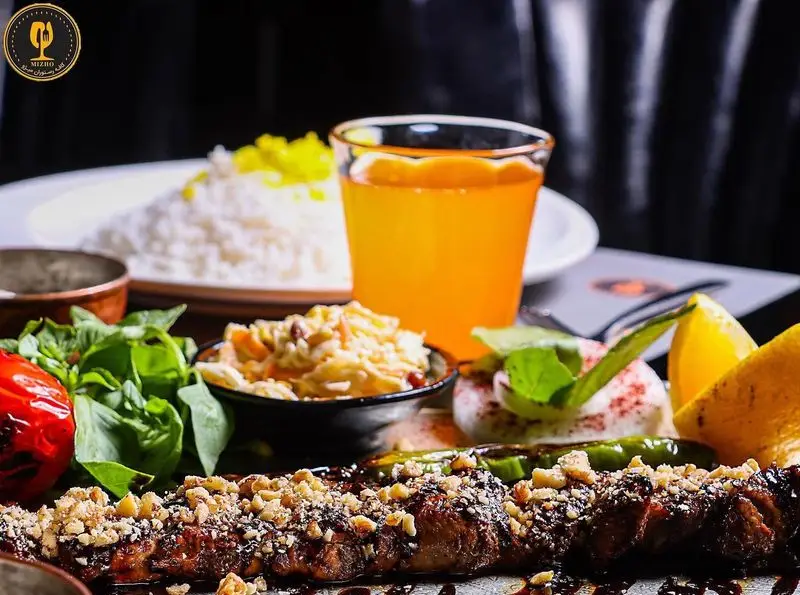 کباب مخصوص کافه رستوران میژو، با آجیل و سس خاص، برنج زعفرانی، گوجه، سبزیجات تازه، سالاد و آبمیوه پرتقال. تجربه غذایی اصیل ایرانی.