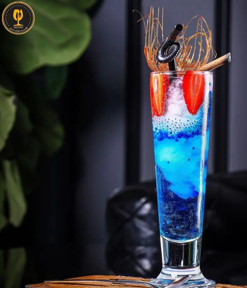 نوشیدنی لایه لایه و رنگارنگ کافه رستوران میژو با تزیینات کاراملی، توت فرنگی و دانه چیا، تجربه‌ای خنک و دلپذیر.