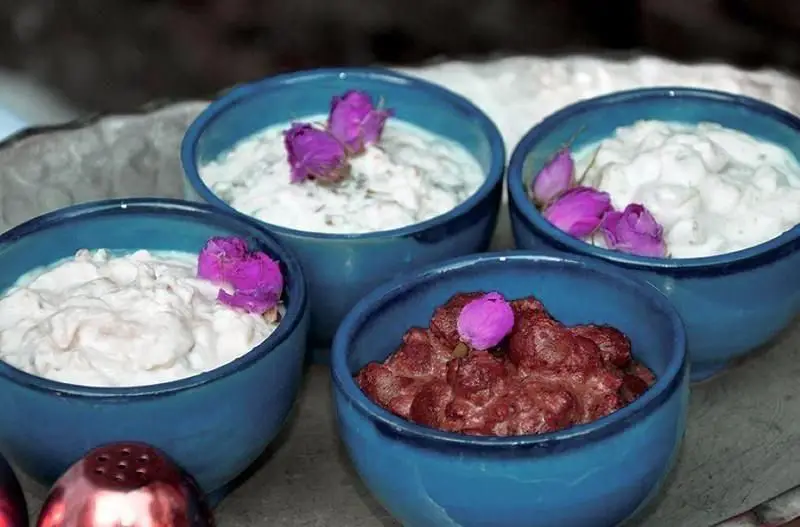 چند کاسه سفالی آبی حاوی ماست سنتی ایرانی و دسر با تزئین گل محمدی، نمادی از طعم اصیل در رستوران ایرانی سلطانی.