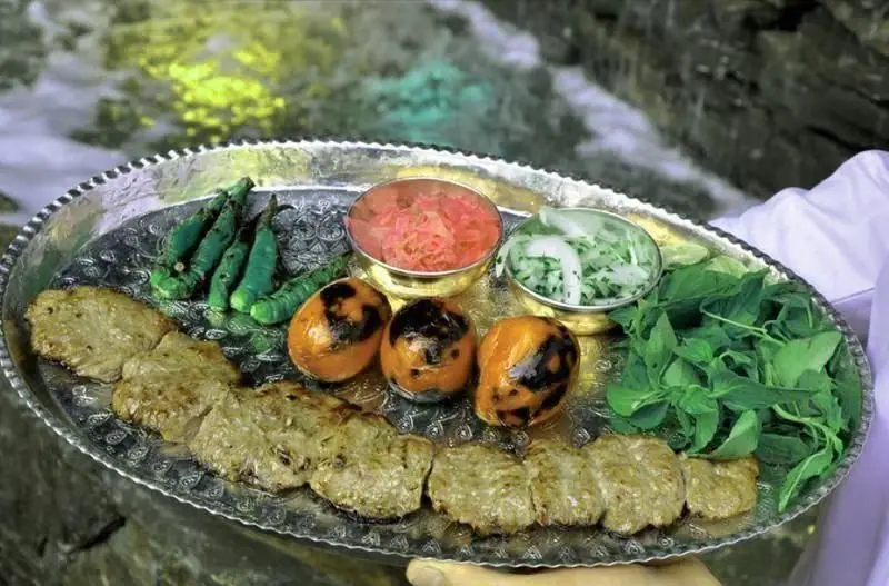 کباب کوبیده و مخلفات لذیذ ایرانی رستوران سلطانی، شامل گوجه و فلفل کبابی، سبزی و سالاد در کنار رودخانه، یک تجربه غذایی بی‌نظیر.