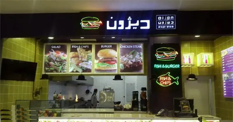 نمایی از رستوران فست فود دیژون اکسپرس در مرکز خرید سانا با تابلوهای نئونی برگر و ماهی، ارائه دهنده برگر، ماهی و چیپس، سالاد و چیکن استیک.