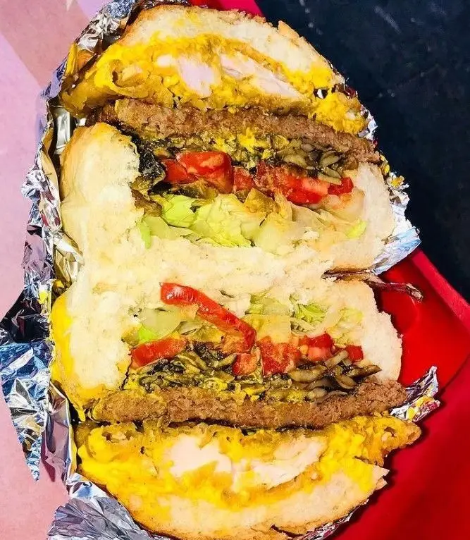 ساندویچ غول‌پیکر و پرملات فست فود ترافیک با ترکیبی از مرغ، همبرگر، کاهو، گوجه، قارچ و سس‌های مخصوص، آماده سرو در فویل.