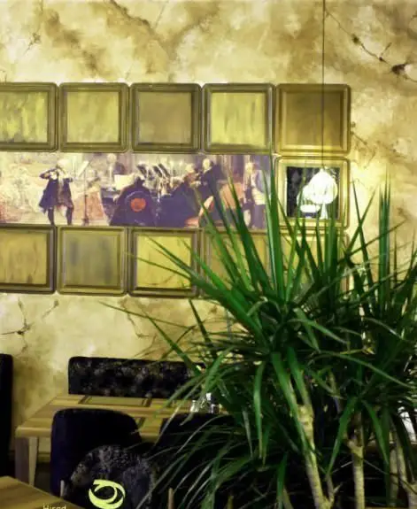 تصویری از فضای دلنشین و دکوراسیون زیبای داخلی رستوران هیراد، شامل میز و صندلی‌های مجلل، گیاهان آپارتمانی و تابلوهای دیواری منحصربه‌فرد.