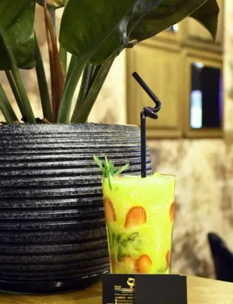 نوشیدنی خنک و گوارا با توت فرنگی و نعناع در لیوان شفاف، در کنار گلدان بزرگ در فضای دلنشین رستوران هیراد.