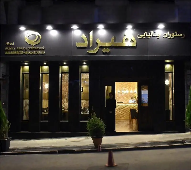 رستوران هیراد ایتالیایی لوکس در شب، نمای بیرونی جذاب با تابلو طلایی و ورودی روشن، بهترین انتخاب برای شام.