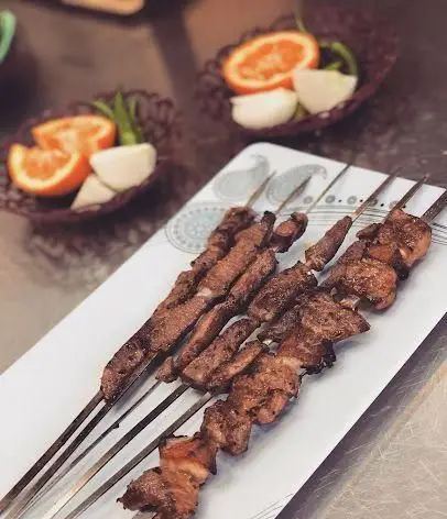 سیخ های داغ جگر و کباب لذیذ جگرکی پاتوق، همراه با برش های پرتقال و پیاز، طعمی اصیل از غذای سنتی ایرانی.