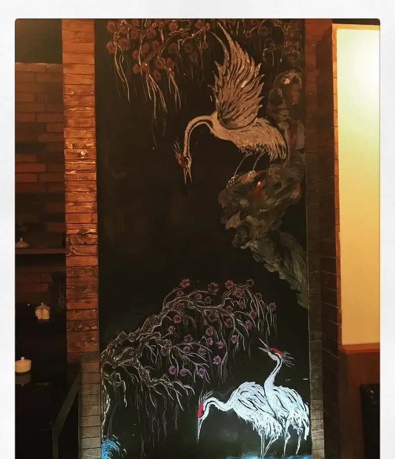 فضای داخلی رستوران و تهیه غذای لک لک با نقاشی دیواری شگفت‌انگیز لک لک‌ها، درختان شکوفه‌دار و طرح‌های هنری دلنشین