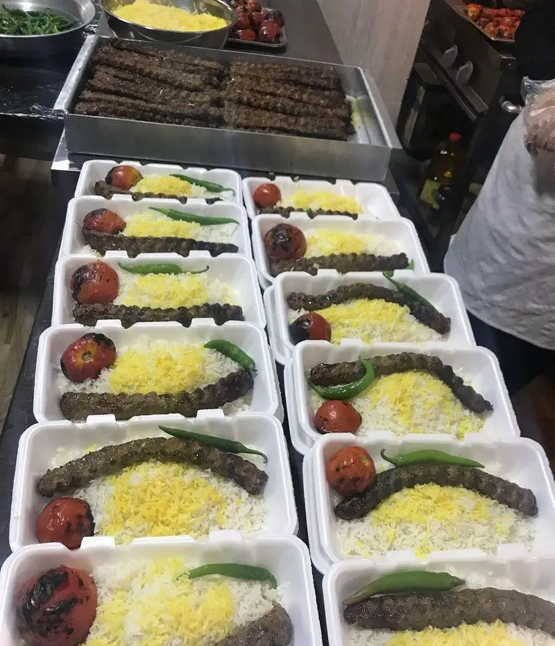 آماده‌سازی انبوه غذاهای لذیذ رستوران و تهیه غذای لک لک: بسته‌های کباب کوبیده با برنج، گوجه و فلفل کبابی برای سفارشات.
