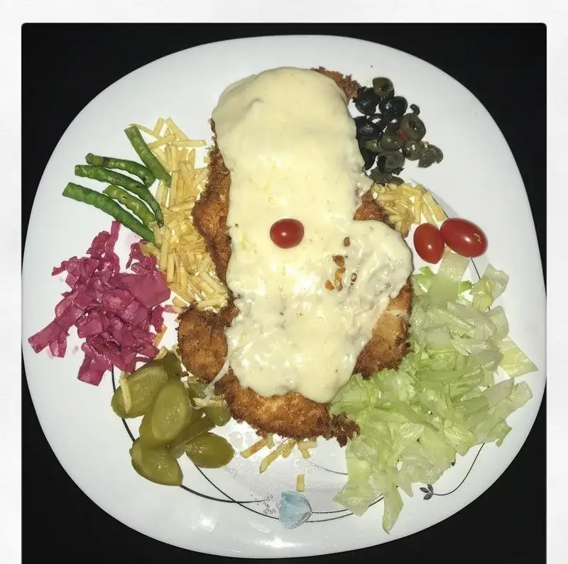 جوجه شنیتسل خوشمزه با سس پنیر، سیب‌زمینی، زیتون، خیارشور و سالاد از رستوران و تهیه غذای لک لک.