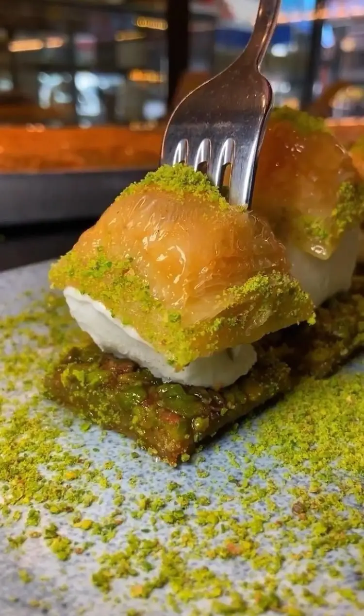 باقلوای ترکی سنتی با بستنی و پسته فراوان، آماده سرو در شعبه علی کیپا پیروزی. دسری لذیذ و دلنشین با چنگال.