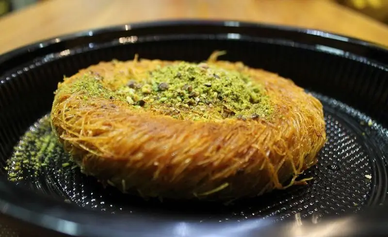 کنافه ترکی خوشرنگ و تازه با رشته‌های طلایی ترد، پوشیده از پودر پسته اعلا، دسری لذیذ از باقلوای ترکی علی کیپا پیروزی.