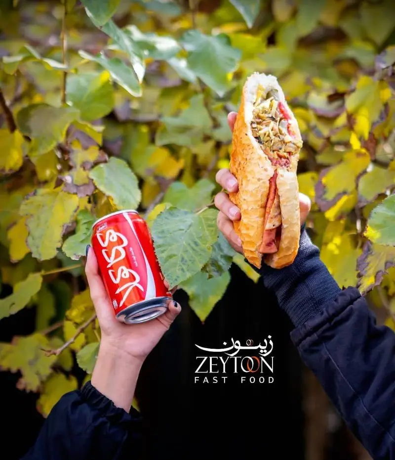 ساندویچ لذیذ پرملات و نوشابه خنک کوکاکولا، تجربه‌ای دلنشین از منوی متنوع رستوران فست فود زیتون را به تصویر می‌کشد.