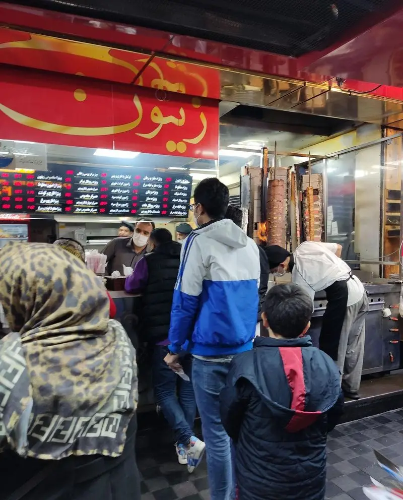 فضای داخلی رستوران فست فود زیتون با مشتریانی که در حال سفارش شاورما و دونر کباب تازه هستند. منو و کارکنان مشغول.