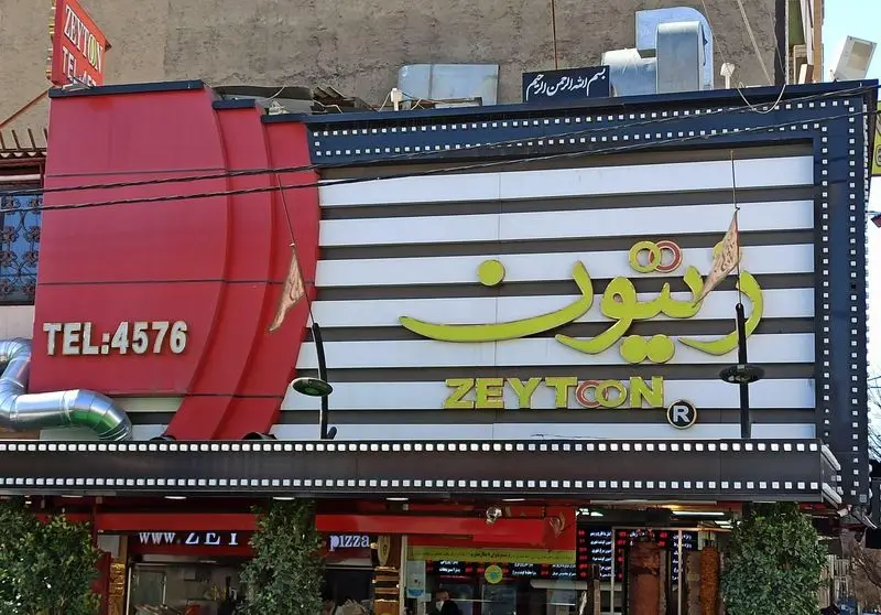 تصویری از تابلوی ورودی رستوران فست فود زیتون، با نوشته‌های "زیتون" (فارسی) و "ZEYTCON" (لاتین) و تلفن 4576.