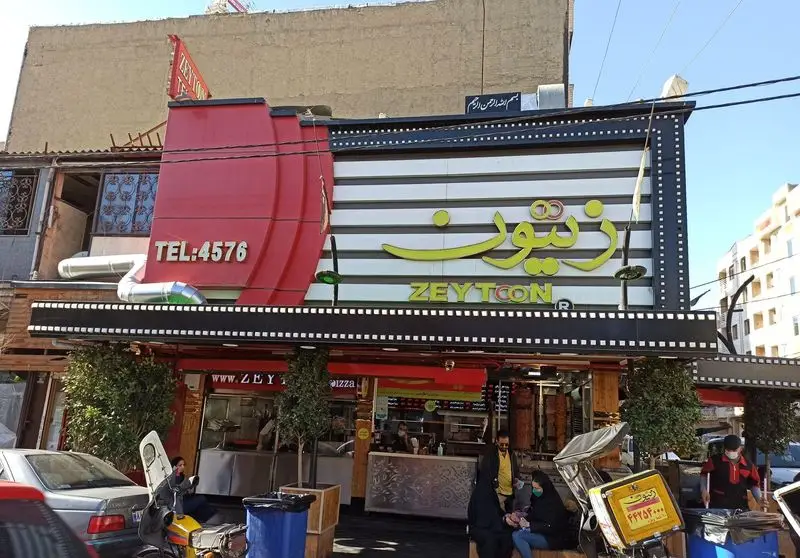 نمای بیرونی شلوغ رستوران فست فود زیتون با تابلوی بزرگ برند زیتون به فارسی و انگلیسی و شماره تماس TEL:4576.