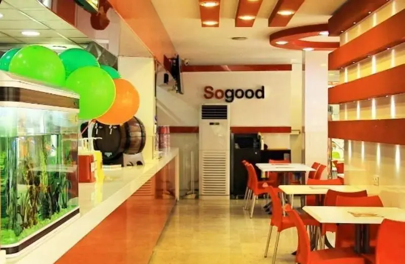 تصویر فضای داخلی دلباز و مدرن رستوران فست فود مرغ سوخاری کوپال با میز و صندلی‌های قرمز و سفید و دکوراسیون جذاب و گرم.