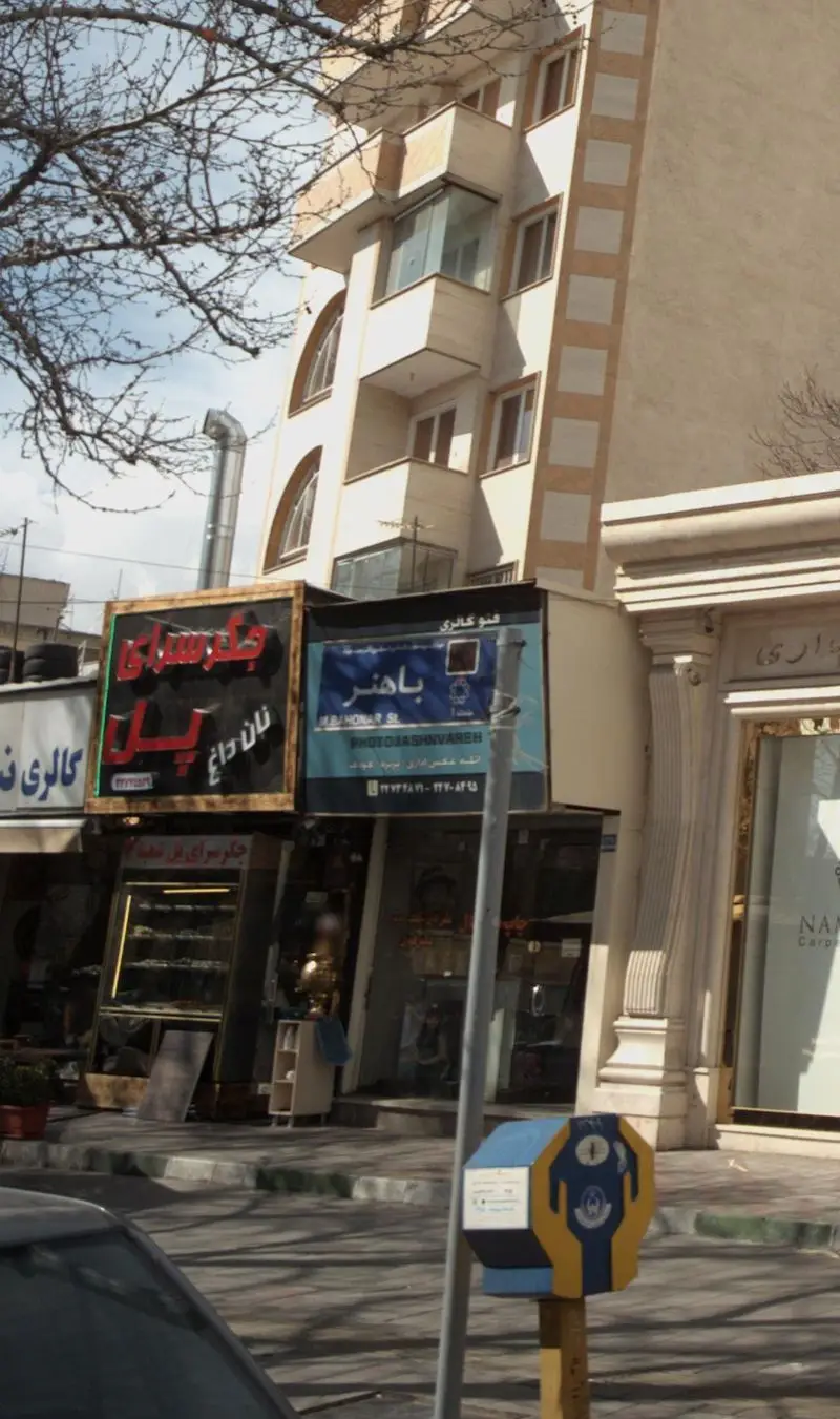 تابلو و ورودی جگر سرای پل با عنوان نان داغ در یک خیابان پرتردد. جزئیاتی از نمای ساختمان و کسب و کارهای مجاور در شهر.