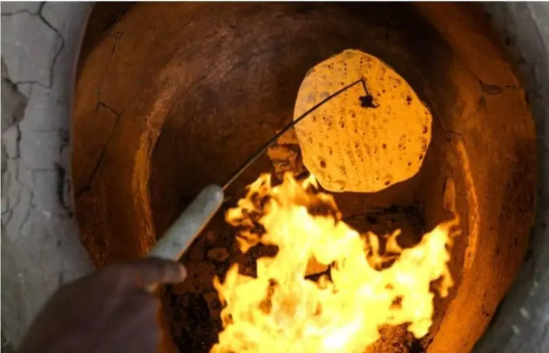آماده سازی نان داغ در تنور سنتی جگرکی کبابی شاطر میرزا، تجربه طعم اصیل کباب و جگر تازه با نان گرم.