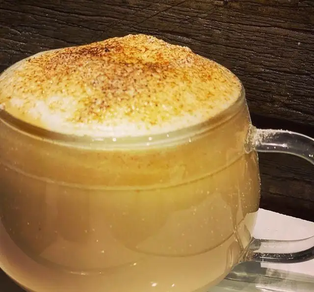 نوشیدنی گرم و دلپذیر کافه سیدمهدی: لاته یا کاپوچینو با فوم غلیظ و پودر دارچین در ماگ شیشه‌ای زیبا، مناسب برای لحظات آرامش‌بخش.