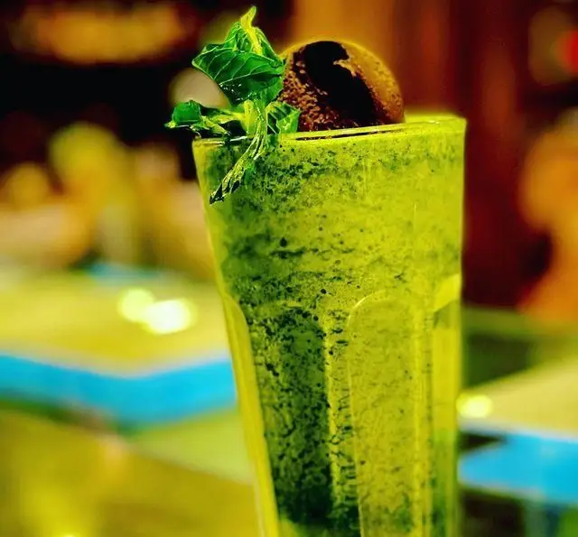 نوشیدنی سبز خنک و گوارا در کافه سیدمهدی، با برگ نعنای تازه و تزئینات شکلاتی، تجربه‌ای لذت‌بخش و سلامت‌بخش برای مشتریان کافه.