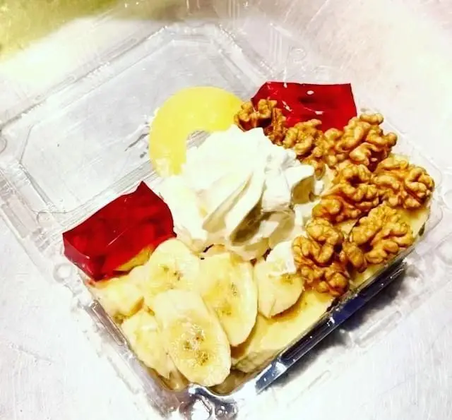 دسر میوه تازه و لذیذ کافه سیدمهدی شامل موز، خامه، ژله، کمپوت هلو و گردو. آماده برای سفارش و تحویل.