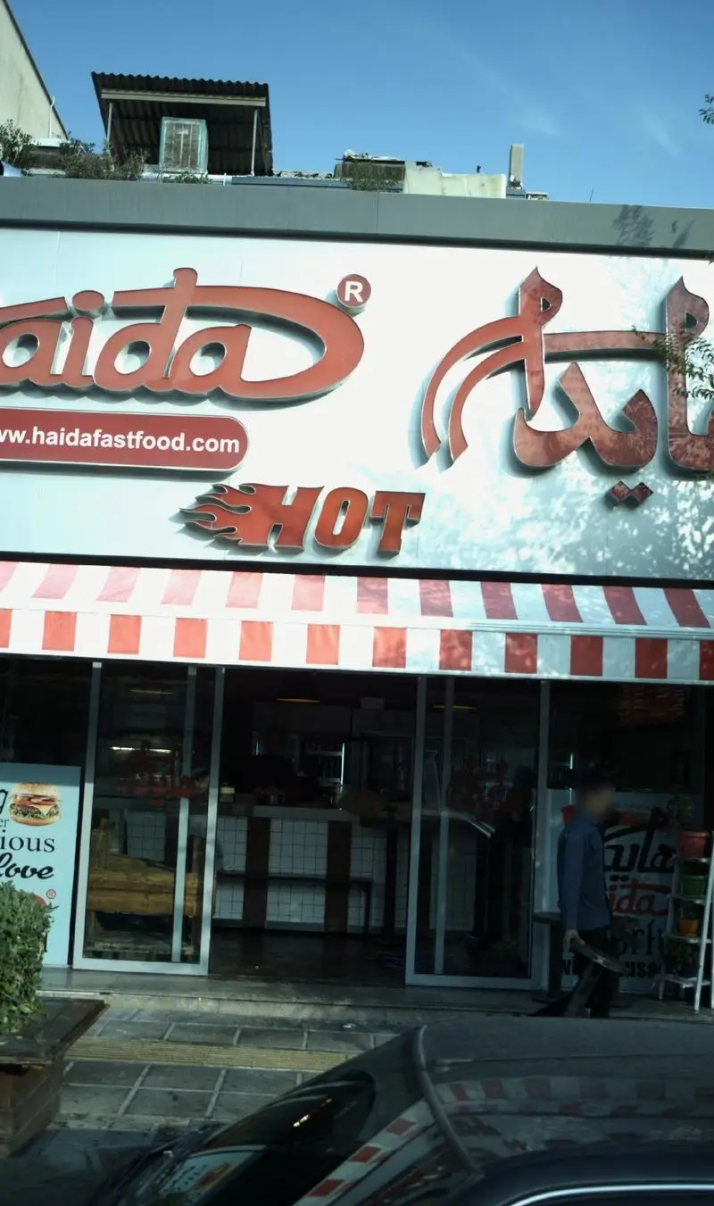 تصویری از نمای خارجی رستوران فست فود هایدا با لوگوی درخشان و آدرس وب‌سایت haidafastfood.com، مکانی عالی برای ساندویچ‌های داغ و لذیذ.