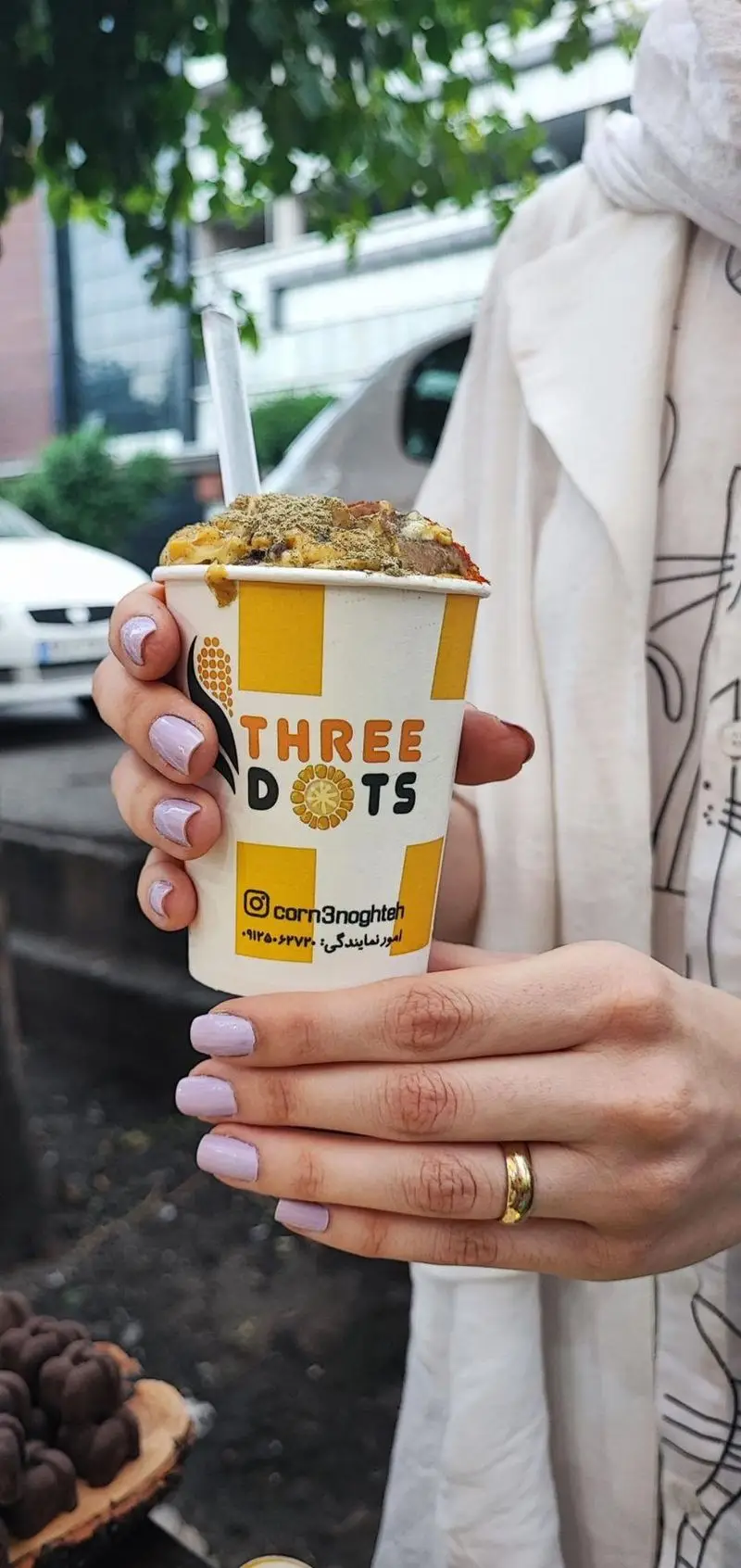 مشتری خوشحال در حال لذت بردن از ذرت مکزیکی لذیذ سه نقطه، با ادویه‌های مخصوص در شعبه کارگر شمالی تهران.