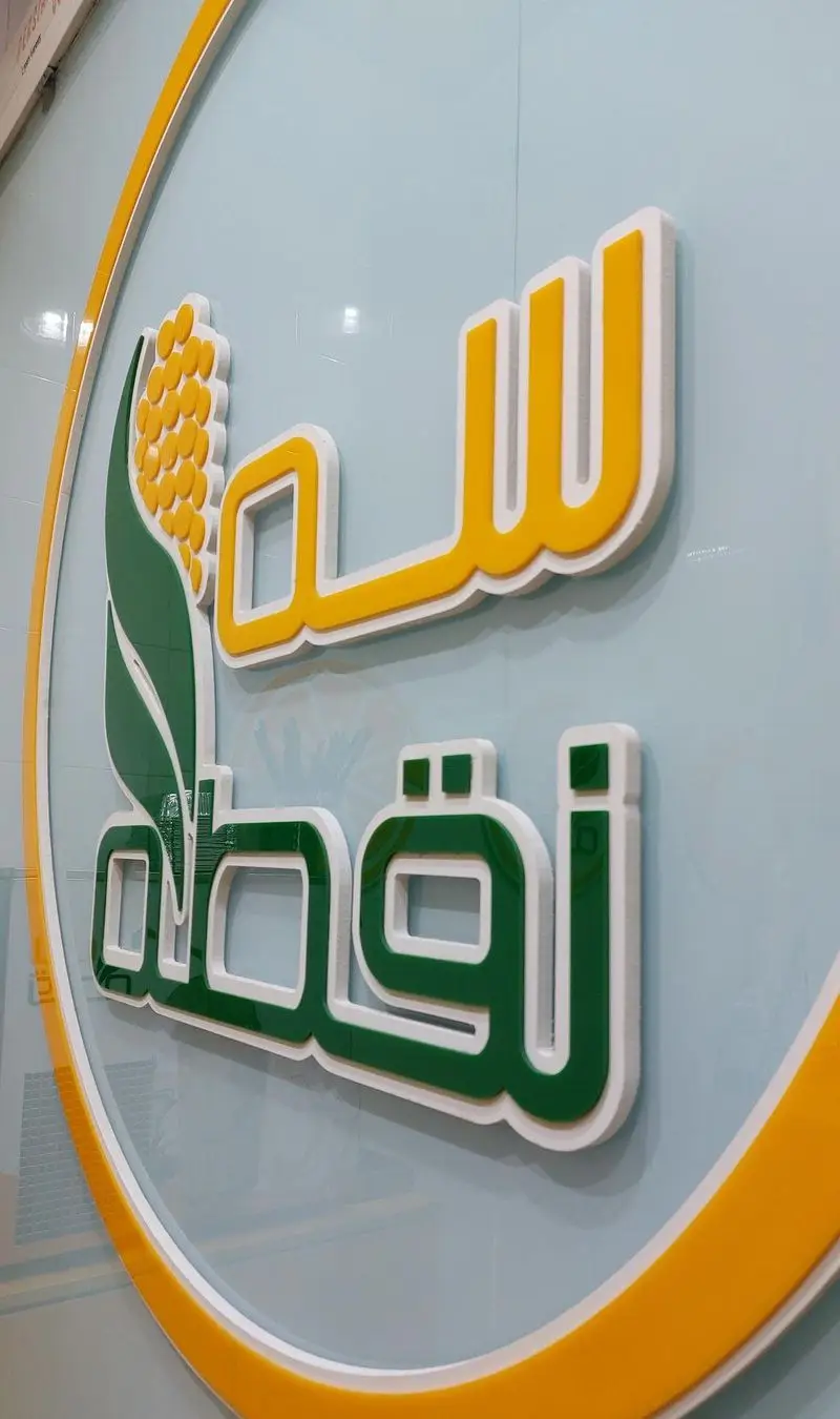 تابلوی سه بعدی ذرت مکزیکی سه نقطه کارگر شمالی با طرح دانه ذرت، لوگوی زرد و سبز و قاب دایره‌ای سفید و زرد.