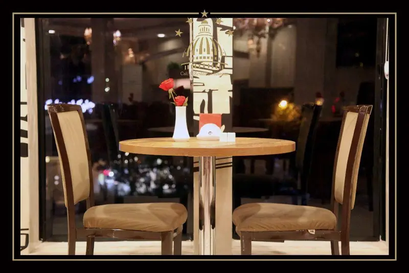 میز و صندلی دنج و رمانتیک در کافه و رستوران مجموعه پذیرایی خيام. گل رز قرمز، فضای داخلی شیک با نورپردازی گرم و دلنشین.