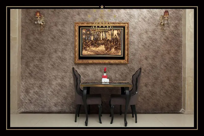 نمایی از دکوراسیون داخلی لوکس مجموعه پذیرایی خیام شامل میز غذاخوری دو نفره، صندلی‌های خاص و تابلوی دیوارکوب هنری با آباژورهای کلاسیک.