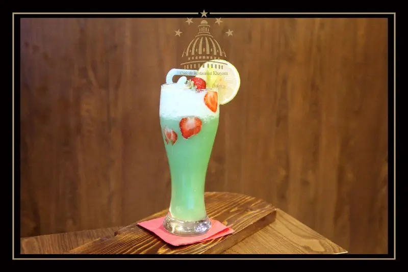 اسموتی نعنا لیمو و توت فرنگی تازه در لیوانی بلند، روی تخته چوبی، در کافه و رستوران مجموعه پذیرایی خیام.