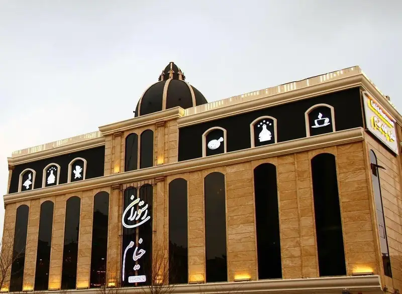 نمای بیرونی مجلل مجموعه پذیرایی خيام با معماری کلاسیک، گنبد مشکی و پنجره‌های بلند، نشان‌دهنده فضایی لوکس برای رستوران و کافه.