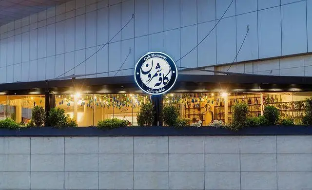 نمای بیرونی کافه شمرون با تابلوی گرد و نورانی خاطره بازی، ورودی شیک و مدرن کافه رستوران شمرون در تهران.