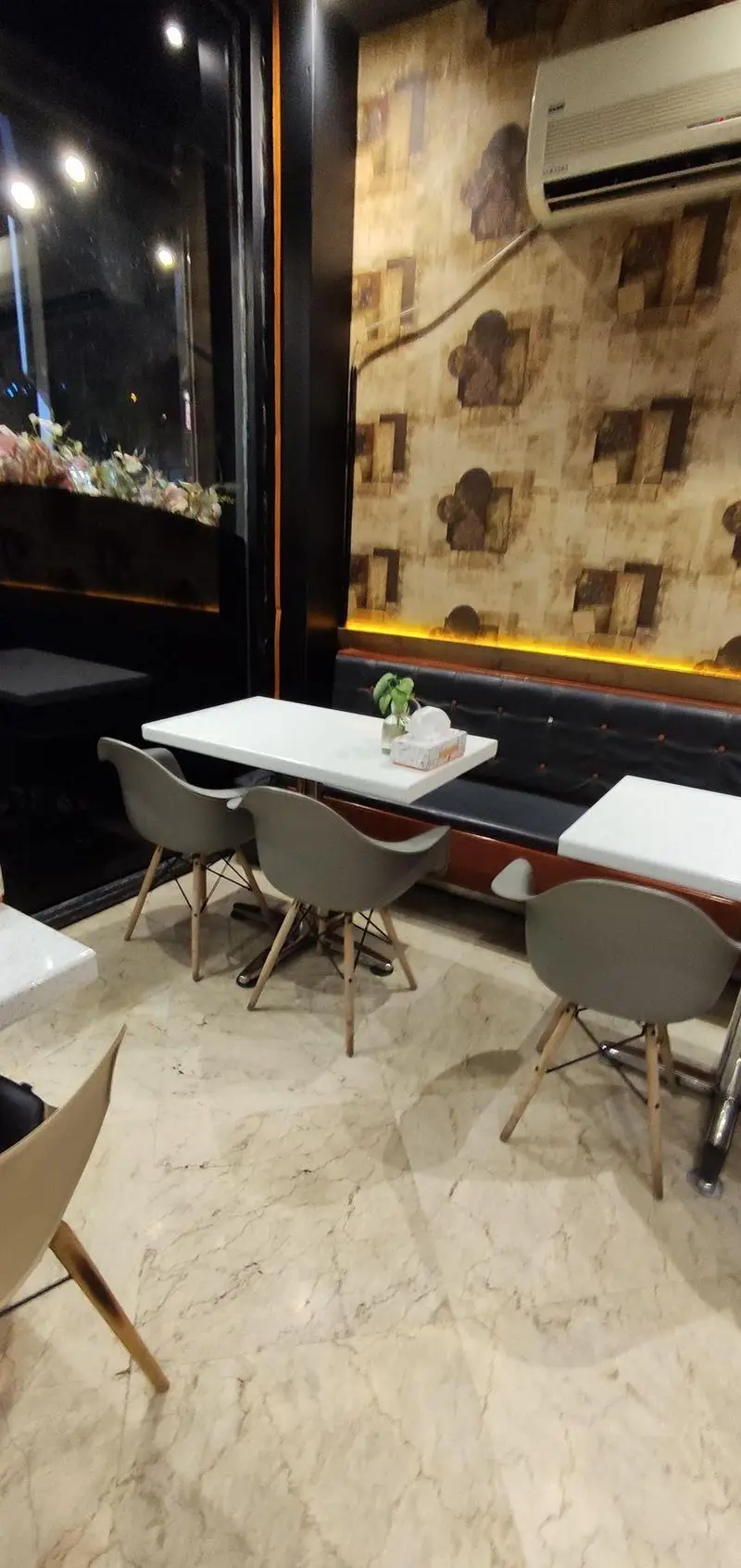 نمایی از دکوراسیون داخلی فست فود پاییز با میز و صندلی‌های شیک، مبلمان چرمی، کف مرمر و نورپردازی گرم، محیطی دنج برای صرف غذا.