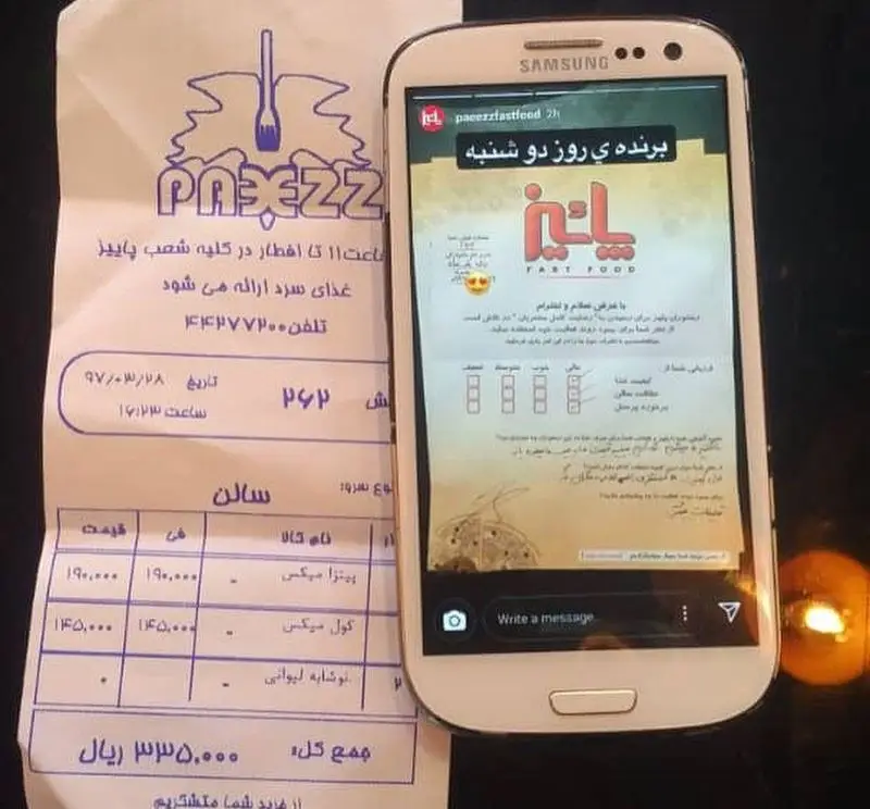 رسید خرید فست فود پاییز (پیتزا، نوشابه) و گوشی هوشمند با صفحه اینستاگرام @paeezzfastfood نمایشگر مسابقه یا نظرسنجی.