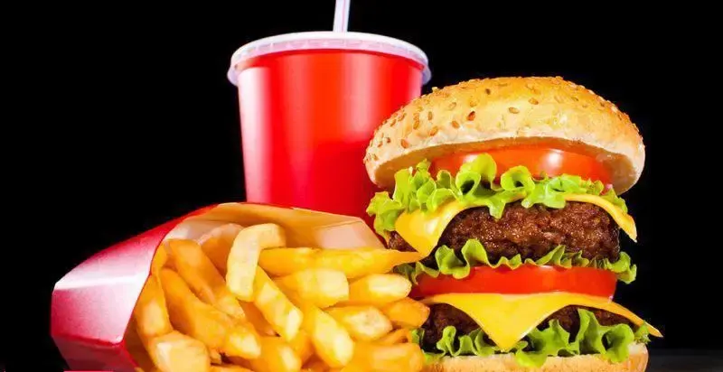 تصویری جذاب از منوی فست فود فان: همبرگر دوبل، سیب زمینی سرخ کرده طلایی و نوشابه خنک. لذت یک وعده غذای آماده خوشمزه.
