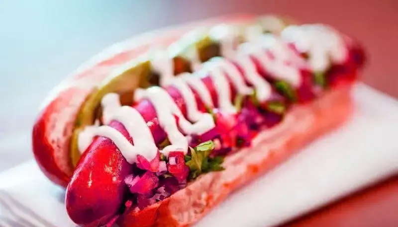 هات داگ ویژه فست فود فان: سوسیس قرمز با پیاز، سبزیجات تازه و سس سفید خامه ای، تجربه طعمی بی نظیر.