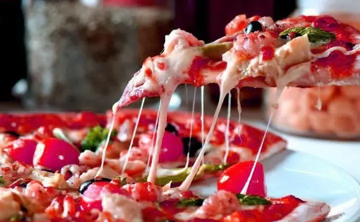 تصویری دلپذیر از پیتزای داغ فست فود فان با پنیر فراوان و کشدار، نشانگر کیفیت و طعم بی نظیر این فست فود.