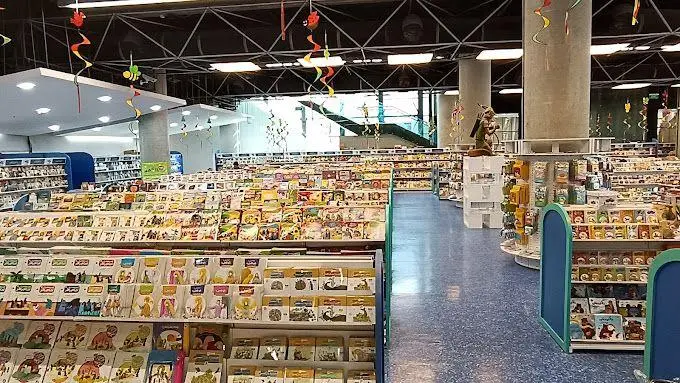 نمای داخلی باغ کتاب تهران، کتابفروشی بزرگ و مدرن با قفسه‌های پر از کتاب کودک و نوجوان، راهروهای وسیع و سقف بلند فلزی.