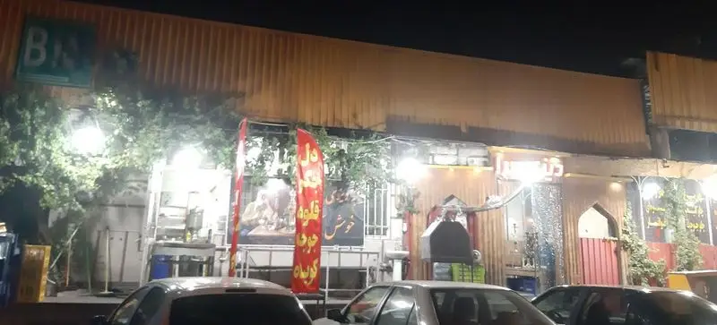 تصویر شب از نمای سرای سنتی پناهی دیزی سرا، رستورانی دلپذیر با غذاهای ایرانی، دیزی و دل و قلوه، در محیطی روشن و پر رفت‌وآمد.